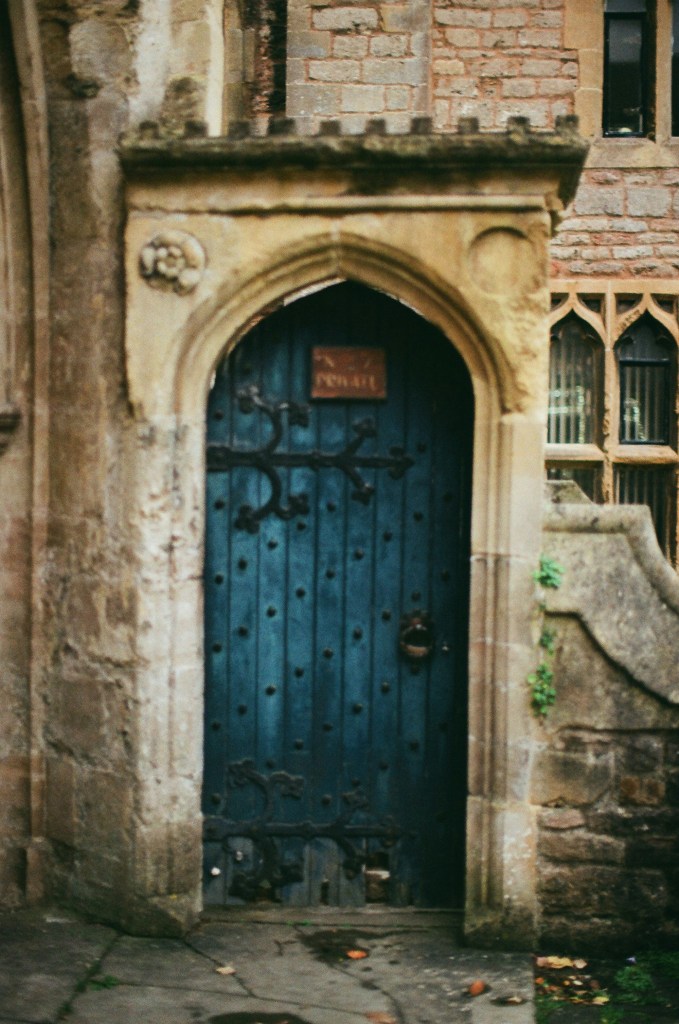 a deep blue door with iron work that is part of a very old stone building.