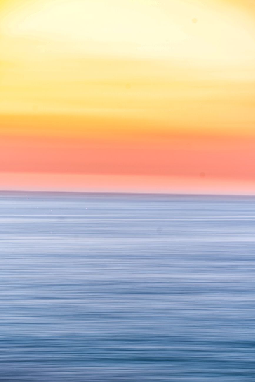 an image that evokes the Aro Ace Sunset flag, starting with yellows, oranges, and corals, fading to shades of blue