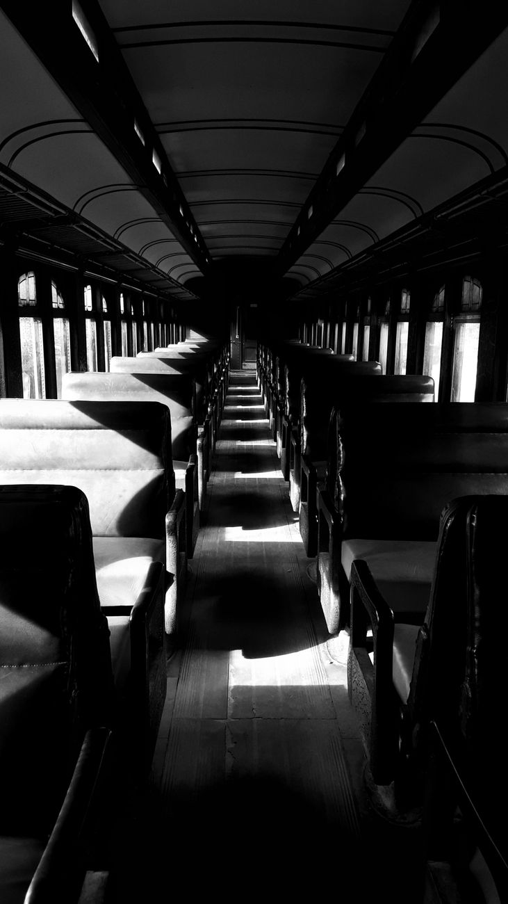 a half-lit black and white interior of a passenger train