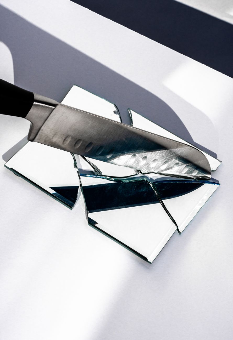 a chef's knife slamming into a mirror on a table
